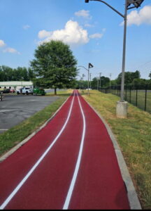 Finished red walking trail with white lane striping installed by JCE, Inc.